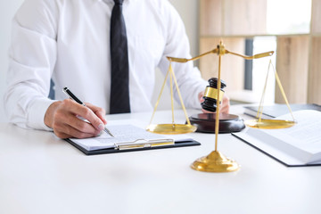 Businessman or lawyer working on a documents, judge gavel with Justice lawyers at law firm in background, Legal law, advice and justice concept