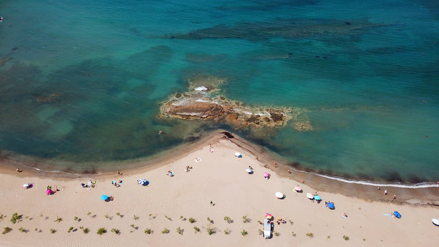 Aerial drone bird's eye view of iconic beach and small islet of Agios Nikolaos, Anavysos, Athens Riviera, Attica, Greece