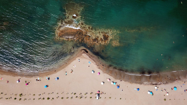 Aerial drone bird's eye view of iconic beach and small islet of Agios Nikolaos, Anavysos, Athens Riviera, Attica, Greece