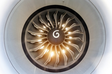 The engine of the airplane is close to the bright light from the sun through the blades.