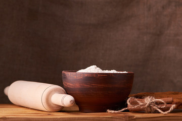 A bowl with flour and apricot cake on a wooden background