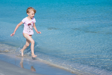 child runs along the edge of the water on the beach