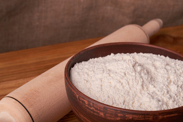 A bowl with flour and apricot cake on a wooden background