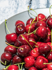 Dark, ripe and juicy cherries on a black plate
