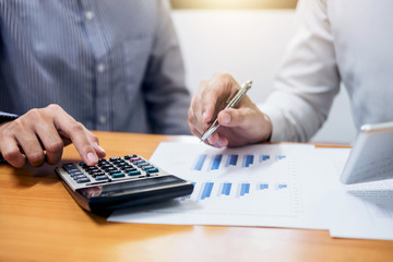 Two business team working Financial investment on calculator with calculate Analyze business and market growth on financial document data graph and digital tablet
