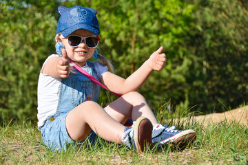 Little girl is playing and laughing on the green lawn in summer
