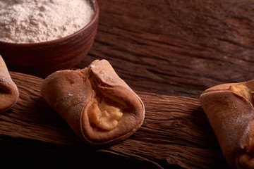 flour, cottage cheese in bowl and milk in a jug. eggs. products for making cheesecakes on a wooden chopping board