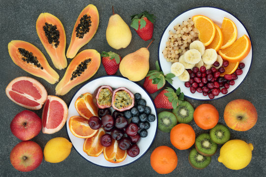 High dietary fibre health food concept with fresh fruit selection on marble background  top view. Foods high in antioxidants, anthocyanins and vitamins.