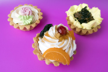 Three different cake buns with cream on a purple background