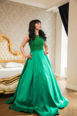 Fototapeta premium Beautiful young girl in a smart expensive emerald dress in luxury suites. Life and the room of a rich girl