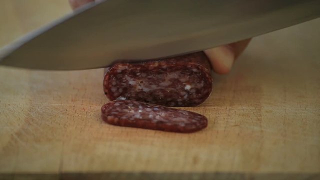 Closeup cutting bulgarian flat sausage called lukanka