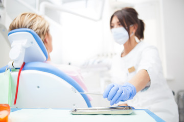 Fototapeta premium A close-up photo of a dentist's hand taking a sterile instrument from a metal tray. Focus on the doctor's hand