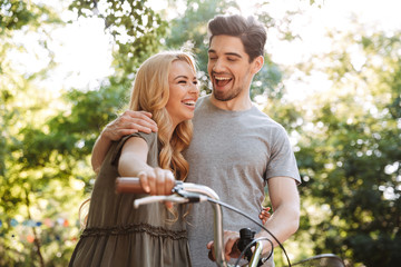 Happy lovely young couple posing together with bicycle