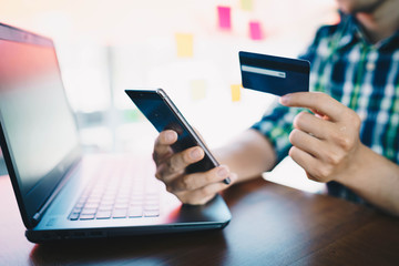 Man using mobile phone and laptop for shopping online by credit card. Pays for purchase.online shopping, online payment,buy and sell products & services.