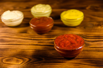Different sauces in glass bowls on wooden table