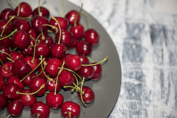 Dark, ripe and juicy cherries on a black plate