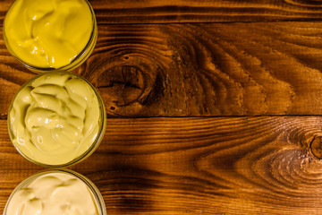 Different sauces in glass bowls on wooden table. Top view