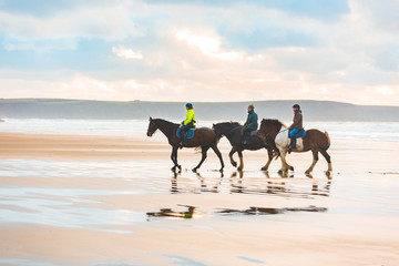 Fototapeta na wymiar Horse riding on the beach at sunset in Wales