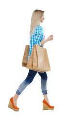 Side view of going  woman  with shopping bags . beautiful girl in motion.