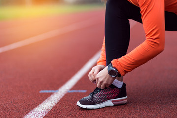 Woman runner tying shoelaces with copy space