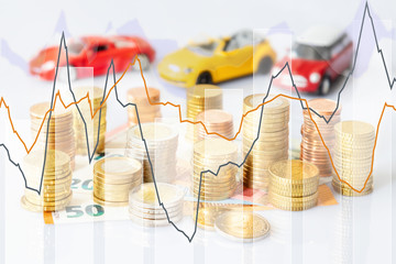 Euro coins in pile on Euro banknotes with charts and three cars, financing concept. Germany