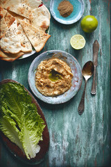 flatlay food background - empty wooden board with hummus, salad and bread, with copy space