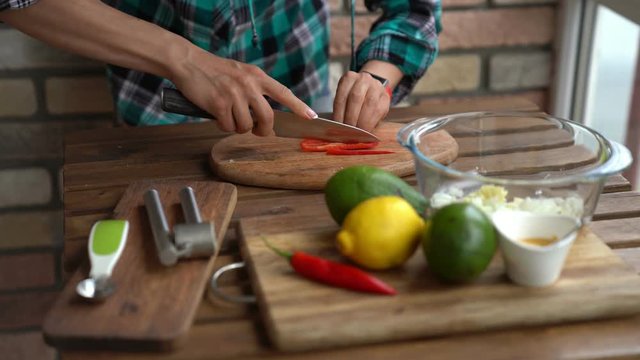 Woman cutting chili peper for guacamole recipe in kitchen 