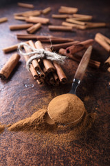 Cinnamon sticks and powder in spoon .