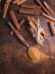 Cinnamon sticks and powder in spoon on a old copper table .