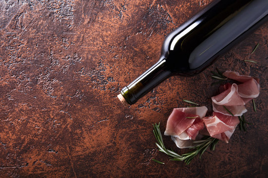 Prosciutto with rosemary and bottle of red wine.