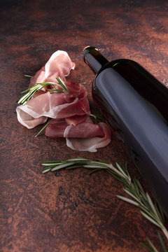 Prosciutto with rosemary and bottle of red wine.