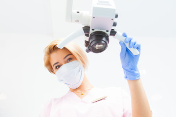 Professional dental endodontic binocular microscope in a treatment room A female doctor looks at the camera. Bottom view