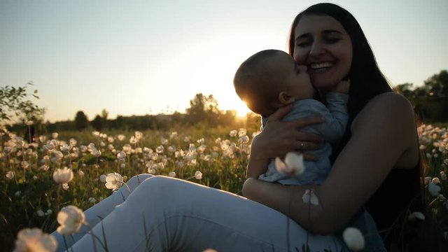 Slow motion of a young happy mother and child in a flower field at sunset.