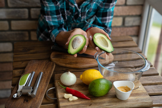young woman cuts avocado on cutting board on table close up