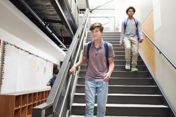 High School Students Walking Down Stairs In Busy College Building