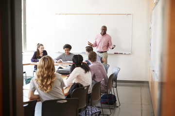 View Through Doorway Of High School Tutor At Whiteboard Teaching Class