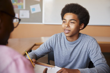 High School Tutor Giving Male Student One To One Tuition At Desk