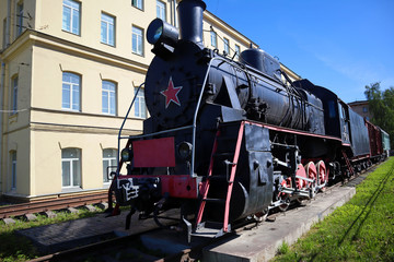 Old russian soviet steam locomotive with wagons standing outdoors on the city street