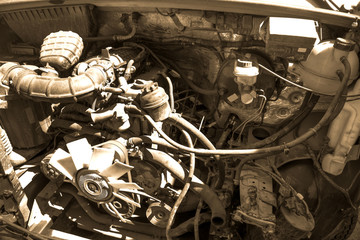 Old broken and dirty car engine close up, view under the hood in sepia tones