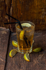 Delicious alcoholic cocktail with lemon and lime, pieces of ice on a wooden background