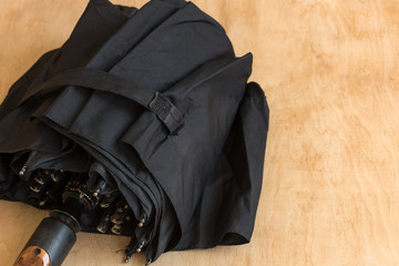 Black umbrella on wooden table. Rain protection. Copy space.