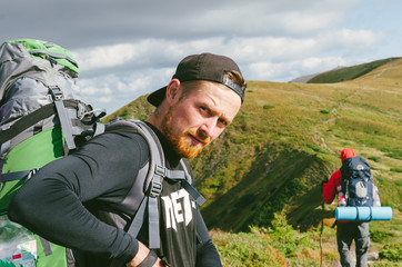 Fototapeta na wymiar Happy hiker with a backpack on trekking in the hills