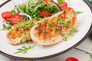Grilled chicken fillet and fresh vegetable salad of tomatoes,red onion and arugula. Chicken meat salad. Healthy food.