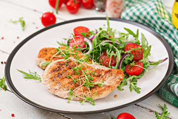 Grilled chicken fillet and fresh vegetable salad of tomatoes,red onion and arugula. Chicken meat salad. Healthy food.