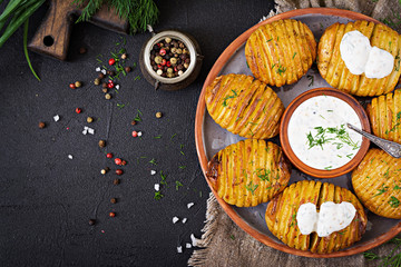 Baked potato with herbs and sauce on black background. Vegan food. Healthy meal. Top view. Flat lay