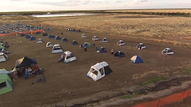 An aerial drone shot of people camping on a wide field.