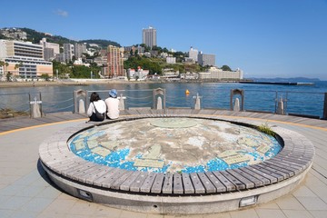 Naklejka premium 熱海の海岸と丘陵に建つマンションと地球儀 崖っぷちに立つ高層マンションが印象的だ