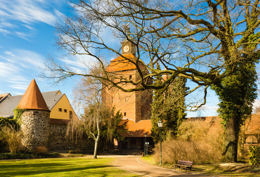 The wintry bare branches of an old tree point to a part of the city wall and the mighty medieval city gate. The Stone Gate dates from the 15th century - Bernau near Berlin, Germany.