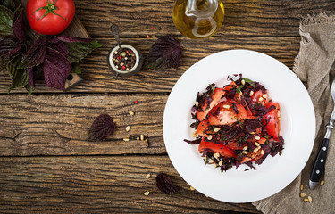 Salad from tomatoes with a violet basil and pine nuts. Vegan food. Italian meal. Top view. Flat lay.