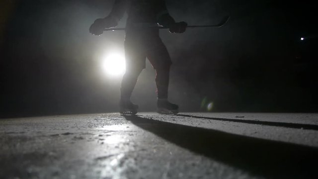 Hockey player running towards camera on skates and doing turn cutting ice